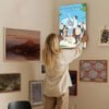 Woman hanging A Silent Voice anime canvas print on gallery wall in modern home interior with mixed art collection.