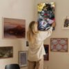 Person hanging Jujutsu Kaisen anime canvas poster on gallery wall with mixed art collection in modern home interior.
