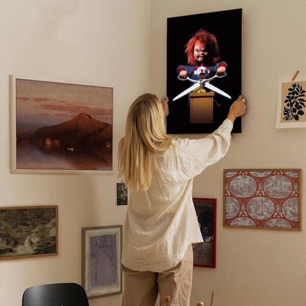 Woman hanging Chucky horror doll artwork on gallery wall surrounded by eclectic art collection in modern home interior