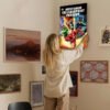 Person hanging DC Justice League Flashpoint Paradox canvas print on gallery wall with mixed art collection in home interior setting.