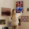 Woman hanging Disney Coco canvas print on gallery wall showing how movie artwork integrates beautifully with modern home decor and art collection.
