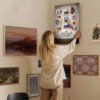 Person hanging Disney Once Upon a Studio canvas print on gallery wall in real home setting showing size and placement with other artwork.