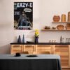 Eazy-E vintage comic book poster displayed as premium wall art in modern contemporary kitchen with wood cabinetry, black countertops, and floating shelves, showcasing how retro hip hop culture integrates with sophisticated culinary space design.