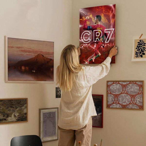 Woman hanging Cristiano Ronaldo CR7 poster on gallery wall in modern home interior with various framed artworks