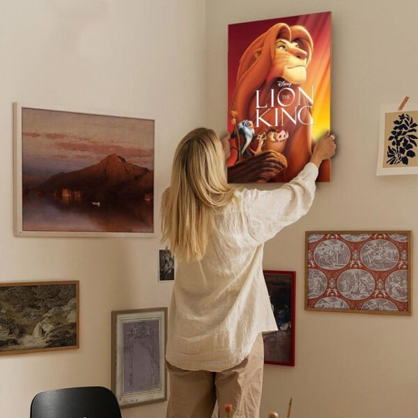 Woman hanging Disney Lion King canvas poster on gallery wall showing home decor installation and interior design styling tips.
