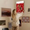 Woman hanging Michael Jordan Air Jordan poster on curated gallery wall with mixed artwork collection
