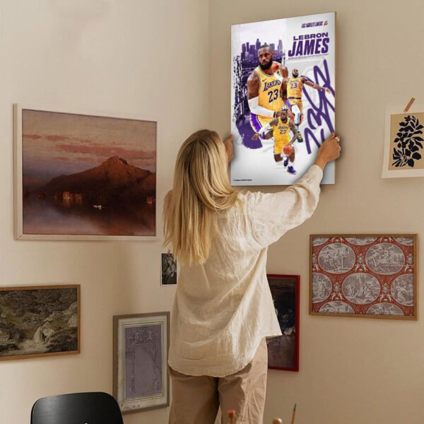 Woman hanging LeBron James Lakers poster on gallery wall with mixed art collection in modern home interior