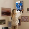 Woman hanging Luka Doncic Dallas Mavericks poster on gallery wall in modern home interior