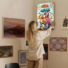 Woman hanging The Mitchells vs The Machines movie poster on gallery wall for home decor