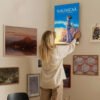 Person hanging Nausicaa of the Valley of the Wind canvas print on gallery wall in modern home interior with eclectic art collection.
