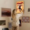 Person hanging Spider-Man Into the Spider-Verse canvas art on gallery wall in home interior with various framed artwork.