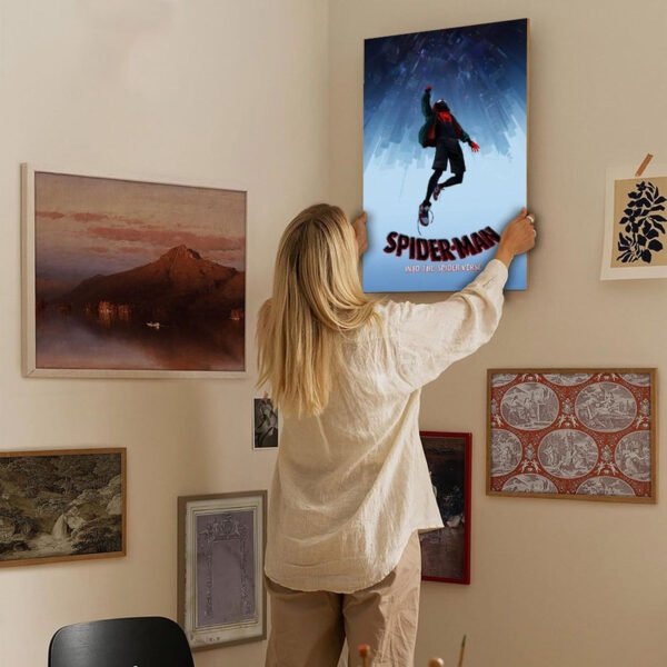 Woman hanging Spider-Man Into the Spider-Verse poster on gallery wall showing home decor styling with movie art integration.