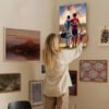 Woman hanging Messi Lamine Yamal inspirational football artwork on home gallery wall with diverse art collection for interior design