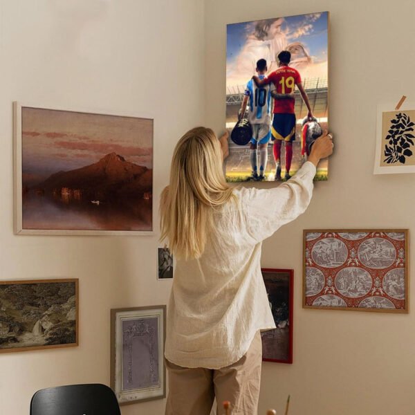 Woman hanging Messi Lamine Yamal inspirational football artwork on home gallery wall with diverse art collection for interior design