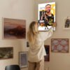 Woman hanging Stephen Curry canvas artwork on gallery wall in modern home interior with curated art collection