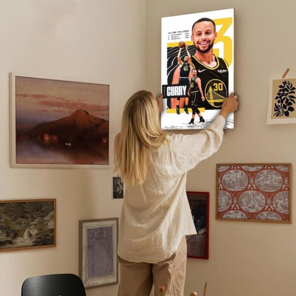 Woman hanging Stephen Curry canvas artwork on gallery wall in modern home interior with curated art collection