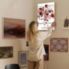 Woman hanging Stephen Curry Warriors canvas art on curated gallery wall in modern home interior design setting