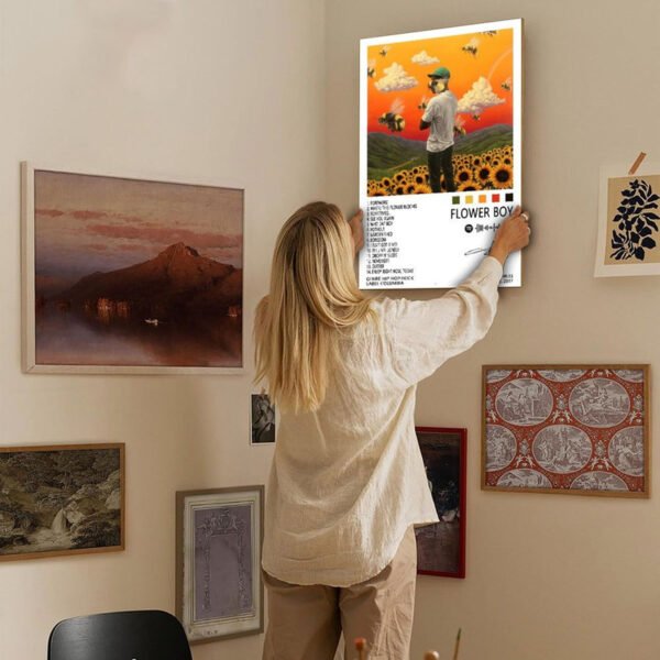 Person hanging Tyler Creator Flower Boy poster on gallery wall with framed artwork for music home decor inspiration