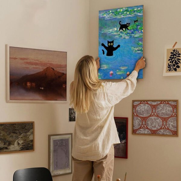 Woman hanging Monet-inspired cat artwork on sophisticated gallery wall with curated art collection in contemporary home setting.